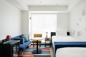 a hotel room with two beds and a blue couch at Aloft Osaka Dojima in Osaka