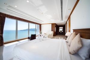 - une chambre avec un grand lit blanc et de grandes fenêtres dans l'établissement Patongtower Duplex Seaview4BR2902, à Patong Beach