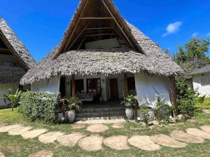 a house with a thatched roof at Cosy Cottage Marine Park - 2 Rooms in Malindi