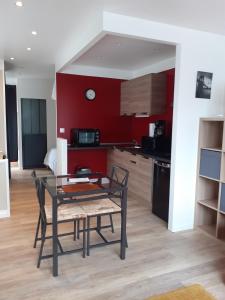 una mesa y sillas en una cocina con paredes rojas en Mini Loft en Saintes