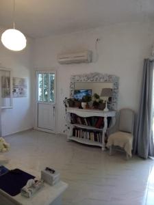 a white living room with a table and a chair at Marathon agios panteleimon attiki Greece in Panayía Mesosporítissa