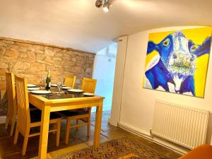une salle à manger avec une table et un tableau mural dans l'établissement Large, characterful cottage in Buxworth, High Peak, à Buxworth