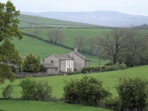 een oud huis midden in een groen veld bij 2 Hull House Cottage in Skipton