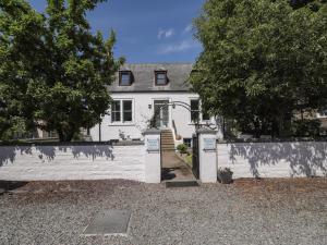 una casa blanca con una valla blanca y árboles en Mary Ann Villa, en Inverness