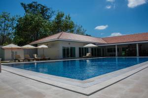 a swimming pool with chairs and umbrellas next to a house at Villa Tha Maphrao in Ban Pa Khlok