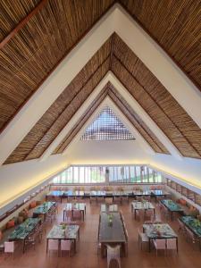 Costa Celine Beach Resort في Kinablañgan: غرفة كبيرة بها طاولات وكراسي ونافذة كبيرة