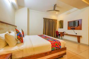 a bedroom with a bed and a desk and a television at FabHotel Shakthi Suites - Nr Jayadeva Hospital in Bengaluru