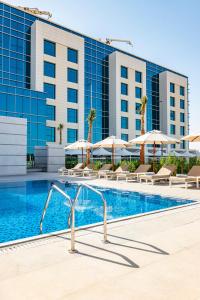 una piscina con sillas y sombrillas frente a un hotel en Remal Hotel, en Al Ruways