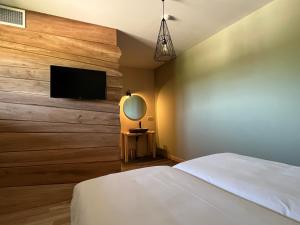 a bedroom with a bed and a flat screen tv at Hôtel En Tilleul in Pont-du-Navoy