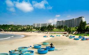 a beach with blue beach chairs on the sand at Jack's Home - Ocean Vista Condotel Sealink Mui Ne in Mui Ne