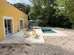 2 sillas y una piscina frente a una casa en Brand new villa with fully intergrated Air conditioning & private pool, Overlooking forest, en Sardan