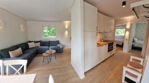 a living room with a blue couch and a kitchen at Nygård Cabins - brandnew holiday home with 3 bedrooms in Sunne