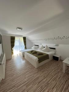 a white bedroom with two beds and a window at Casa Mia in Moieciu de Sus