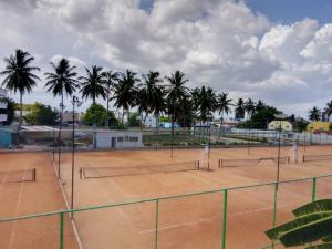 a tennis court with palm trees in the background at Aathira's 2 Bedroom house @ Heart of Coimbatore in Coimbatore