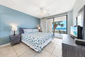 a bedroom with a bed and a tv and a balcony at White Caps 204 in Orange Beach