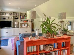 een woonkamer met een blauwe bank en een tafel met boeken bij The Stable in Camerton