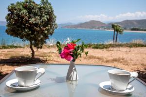 a table with two coffee cups and a vase with flowers at Balos Beach in Kissamos