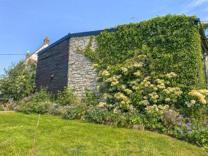 een stenen huis met een heg bloemen bij The Stable in Camerton