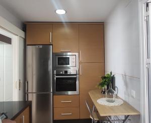 a kitchen with a stainless steel refrigerator and a table at PC CHICLANA, PARKING, WIFI, aire, confort in Chiclana de la Frontera