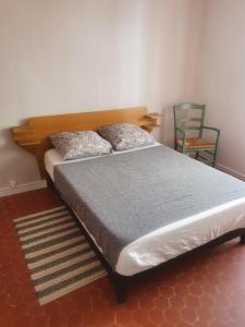 ein Bett mit zwei Kissen und einem Stuhl in einem Zimmer in der Unterkunft La Baieta in Moulinet