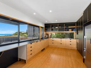 a kitchen with a large window and wooden floors at The Black House in Arrawarra +16 photos