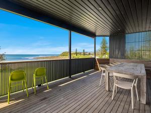 a deck with a table and chairs and the ocean at The Black House in Arrawarra