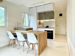 een keuken met een houten tafel en witte stoelen bij Lovely studio apartment near Porto Novi marina in Herceg-Novi