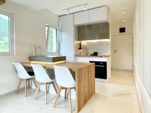 a kitchen with a wooden table and white chairs at Lovely studio apartment near Porto Novi marina in Herceg-Novi