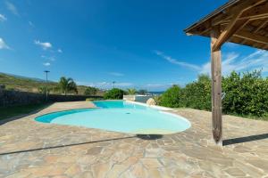 a large swimming pool on a stone patio with a wooden roof at Le Cocon du Lagon in La Saline les Bains