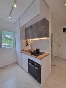 a white kitchen with a sink and a stove at Lovely studio apartment near Porto Novi marina in Herceg-Novi