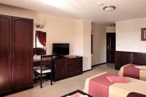 a hotel room with two beds and a desk with a television at House Diona in Sozopol