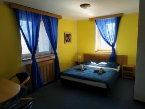 a bedroom with a bed and two windows with blue drapes at Hotel Vyhlídka in Lomnice nad Popelkou