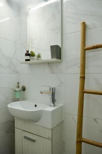 Baño blanco con lavabo y espejo en Holistic Stay, en Avía