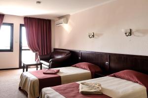 a hotel room with two beds and a chair at House Diona in Sozopol
