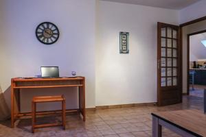 Zimmer mit einem Schreibtisch und einer Uhr an der Wand in der Unterkunft Le Saint-Cyr, Centre-ville, Cosy, Spacieux in Issoudun