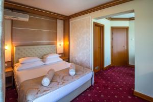 a hotel room with a bed with white pillows at Hotel Cezar Banja Luka in Banja Luka