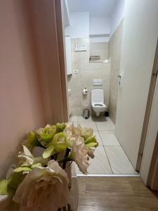 a bathroom with a toilet and a vase of flowers at Apart Mihai Viteazu Residence in Braşov