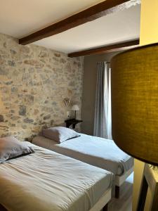 two beds in a room with a stone wall at La Clavelière in Saint-Auban-sur-lʼOuvèze