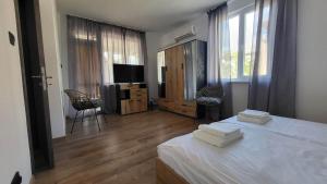 1 dormitorio con 1 cama blanca y TV en Q Аpartment, en Tsarevo