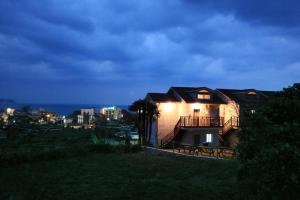 una casa en una colina con las luces encendidas en Capri Hakdong Pension, en Geoje