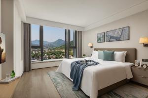 sypialnia z dużym łóżkiem i dużym oknem w obiekcie Citadines Qingshanhu Hangzhou w mieście Hangzhou