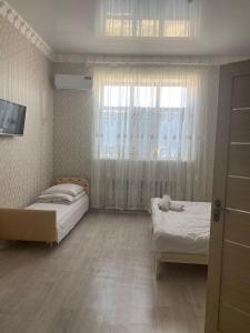 a small bedroom with two beds and a window at Керуен сарайы, гостиница in Aralʼsk