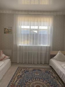 a room with two beds and a large window at Керуен сарайы, гостиница in Aralʼsk