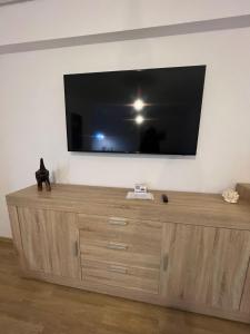 TV de pantalla plana grande en la parte superior de una cómoda de madera en Apart Mihai Viteazu Residence en Brasov