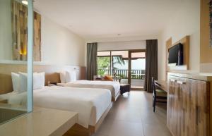 Holiday Inn Resort Baruna Bali, an IHG Hotel في كوتا: غرفه فندقيه سريرين وتلفزيون