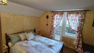 1 dormitorio con 1 cama y una ventana con cortinas en Cabana 2 Râuri, en Bratca