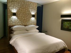 una camera da letto con letto, lenzuola e cuscini bianchi di WaterColors Boracay Dive Resort a Boracay