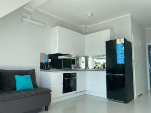 a kitchen with a black refrigerator and a couch at Apartament AQUA MAZURY in Ełk