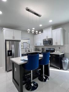 a kitchen with white cabinets and blue bar stools at Luxurious Modern Apartment #4 in Edinburg