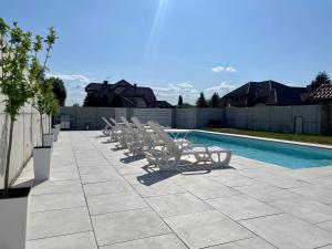 - une rangée de chaises longues à côté de la piscine dans l'établissement Apartament AQUA MAZURY, à Ełk